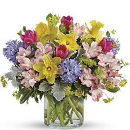 Mixed bouquet of pink, yellow, and purple flowers in a glass vase