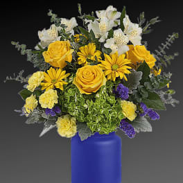 Yellow and white mixed flower arrangement in a blue vase