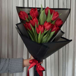 Bouquet of red tulips wrapped in black paper with a red ribbon