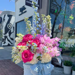 Bouquet of pink roses and pastel flowers in a blue hatbox with a bow