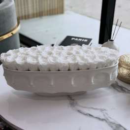 White roses arranged in a low oval ceramic vase