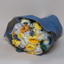Bouquet of yellow and white roses wrapped in blue paper