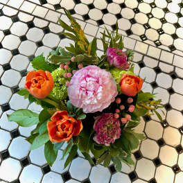Bouquet of pink and orange flowers with greenery on a tiled floor