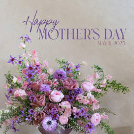 Pink and purple floral arrangement in a lavender pedestal vase