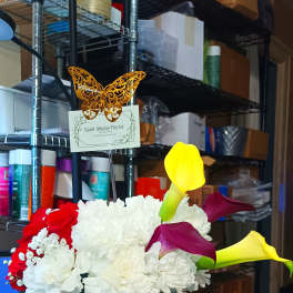 Flower arrangement in a black gift bag with calla lilies and roses, plus a chocolate box
