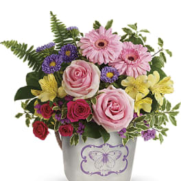 Colorful arrangement of pink roses, gerberas and purple asters in a white pot with butterfly design