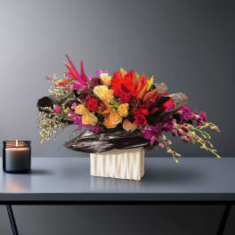 Bright mixed bouquet with roses, lilies, and orchids in a white vase