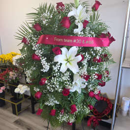 Standing floral spray with red roses and white lilies on an easel