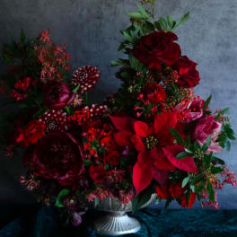 Deep red floral arrangement in a silver pedestal vase