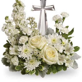 Low white floral arrangement with roses, mums, carnations and a crystal cross in the center