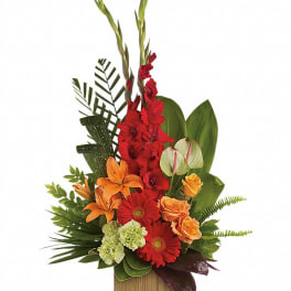 Tall arrangement of red and orange flowers with tropical foliage in a rectangular wooden container