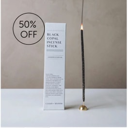 Boxed black copal incense stick beside a lit incense stick