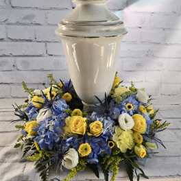 Blue and yellow floral arrangement around a white urn