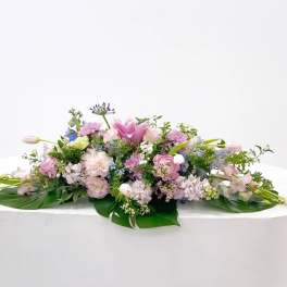 Low floral centerpiece with pink, lavender, and white blooms on a white table