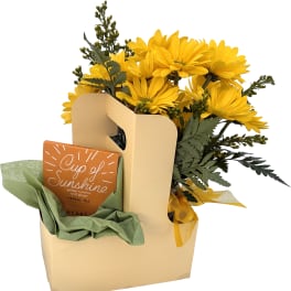 Yellow daisy bouquet in a gift bag with a tea box