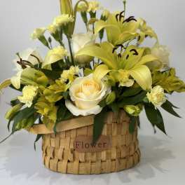 Yellow lilies and roses arranged in a woven basket