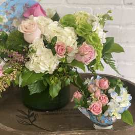 Pink roses and white hydrangeas arranged in a vase with greenery