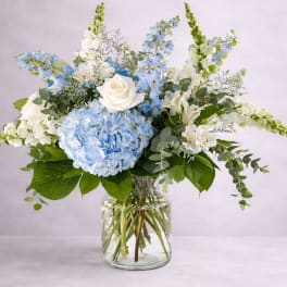 Blue hydrangea and white rose arrangement in a glass vase