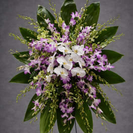 Standing floral spray with white and purple orchids on a metal easel