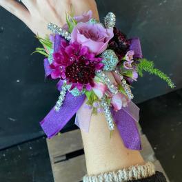 Purple and pink wrist corsage with ribbon and rhinestone accents