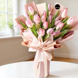 Bouquet of pink tulips wrapped in blush paper with a ribbon