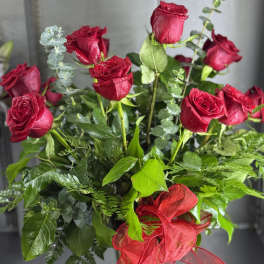Red roses arranged in a clear glass vase with a red ribbon