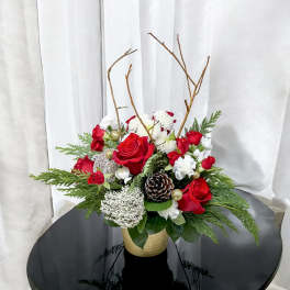 Red roses and white flowers in a gold vase with pinecones and branches