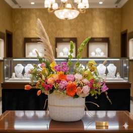 Colorful mixed flower arrangement in a white basket on a table