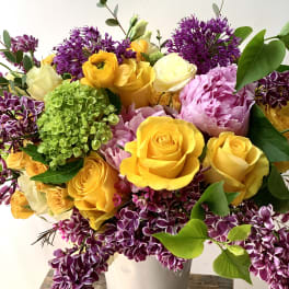 Bouquet of yellow and pink roses with purple flowers in a white vase