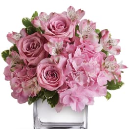 Pink roses and alstroemeria in a clear square vase