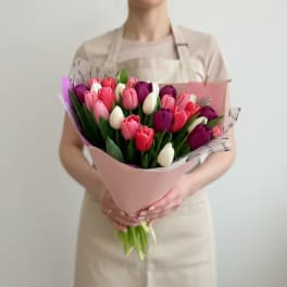 Bouquet of pink, purple, and white tulips wrapped in pale pink paper