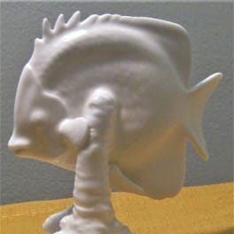 White ceramic fish-shaped figurine on a yellow surface