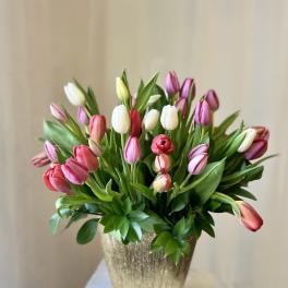 Bouquet of pink, white, and red tulips in a gold vase