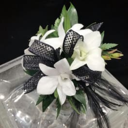 White orchid bouquet with black ribbon accents in a clear vase