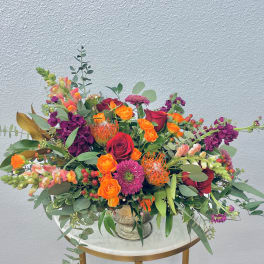 Mixed bouquet of roses, snapdragons, and protea in a silver vase