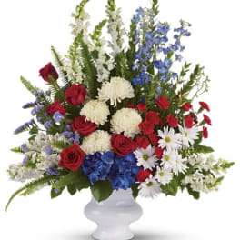 Red, white, and blue mixed flower arrangement in a white vase