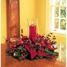 Red candle centerpiece with berries, apples, and pinecones on a table