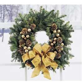 Evergreen wreath with gold pine cones, ornaments, and a large gold bow hanging on a window