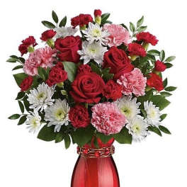 Arrangement of red roses, pink carnations, and white mums in a red glass vase