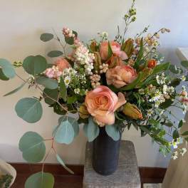 Peach roses and small white daisies in a black vase