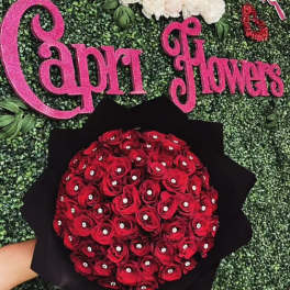 Bouquet of red roses wrapped in black paper against a green backdrop