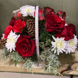 Basket arrangement of red roses and white daisies with pinecones and plaid ribbon