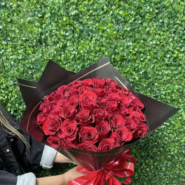 Large bouquet of red roses wrapped in black paper with a red ribbon