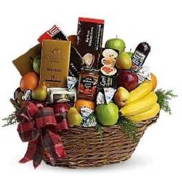 Large wicker gift basket filled with assorted fruits, gourmet snacks, and a plaid ribbon bow
