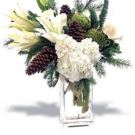 White lilies and hydrangea with pinecones and evergreens in a tall clear glass vase