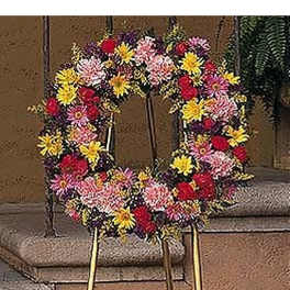 Colorful standing wreath of mixed flowers on a metal easel in front of stone steps