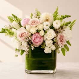 Pink and white roses with ranunculus in a square glass vase