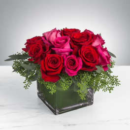 Red and pink roses arranged in a square glass vase