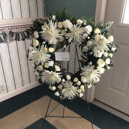 White floral wreath on a black easel stand
