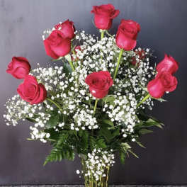 Pink roses arranged in a clear glass vase with white baby's breath